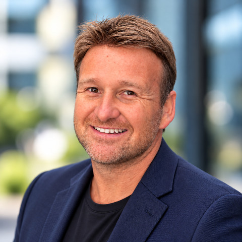 Aaron Jacobs, smiling, in a navy blazer